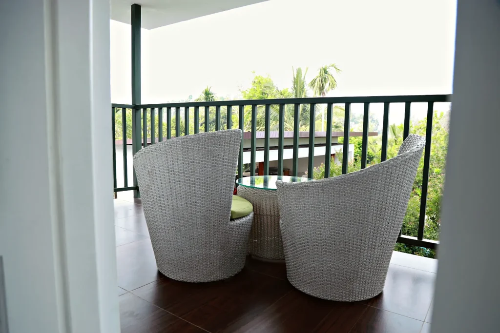 Apartment balcony with rattan chairs and garden view, Le Villagio