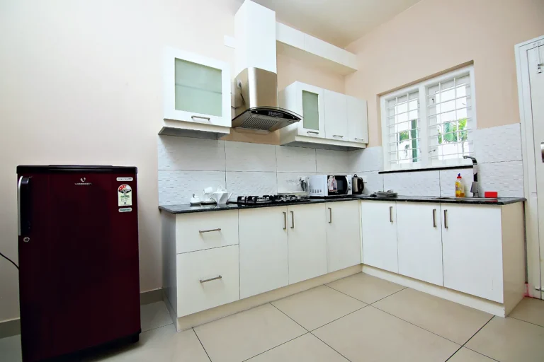 Apartment kitchen with hob, chimney, microwave and refrigerator, Le Villagio Wayanad