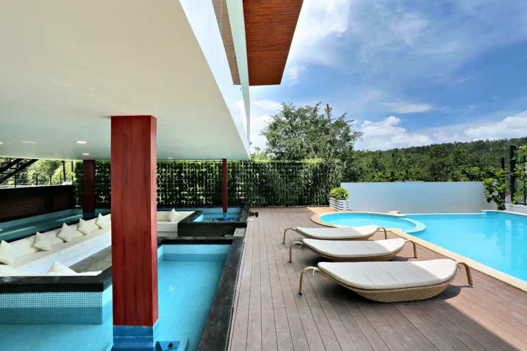 Island pool with sun loungers at Le Villagio Resort, Wayanad